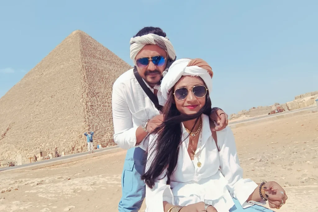 Akash & sumana smiling together for a selfie with the Great Pyramid of Giza in the background.
