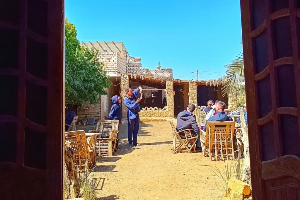 A view looking through a wooden door frame into a rustic Bedouin village house made of mud brick and thatch.