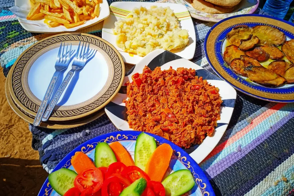 A colorful arrangement of various Egyptian dishes, flatbread, and dips served on a low woven table.