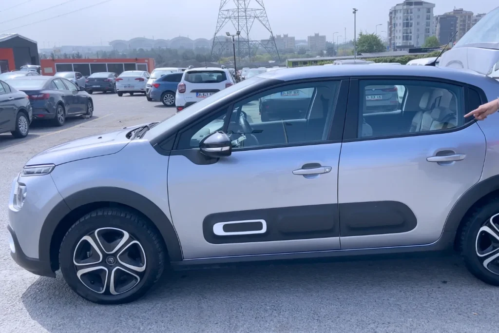 A modern silver Citroën C3 hatchback parked outdoors under a cloudy sky.