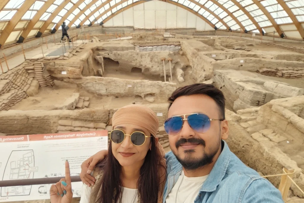 Akash & Sumana taking a selfie inside a modern indoor structural dome covering archaeological excavations.