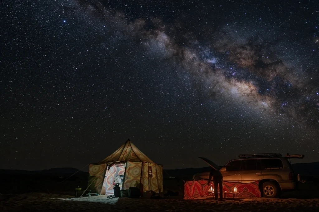 A night shot of a small white tent illuminated from within under a pitch-black sky.