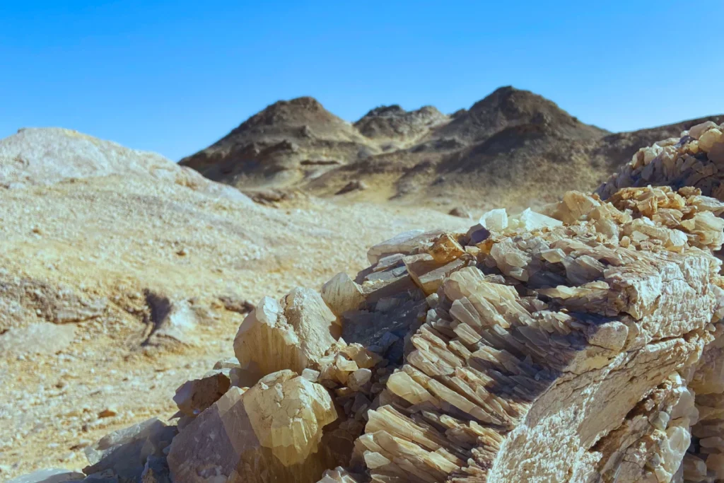 A distinct rocky ridge featuring exposed, glistening quartz crystal formations embedded within the desert soil.
