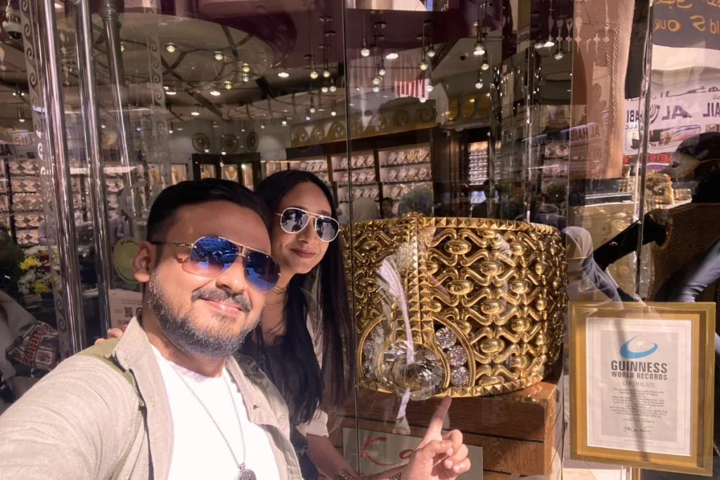Akash and Sumana posing together inside a gold jewelry store, with Akash holding up an incredibly large gold ring that holds the Guinness World record