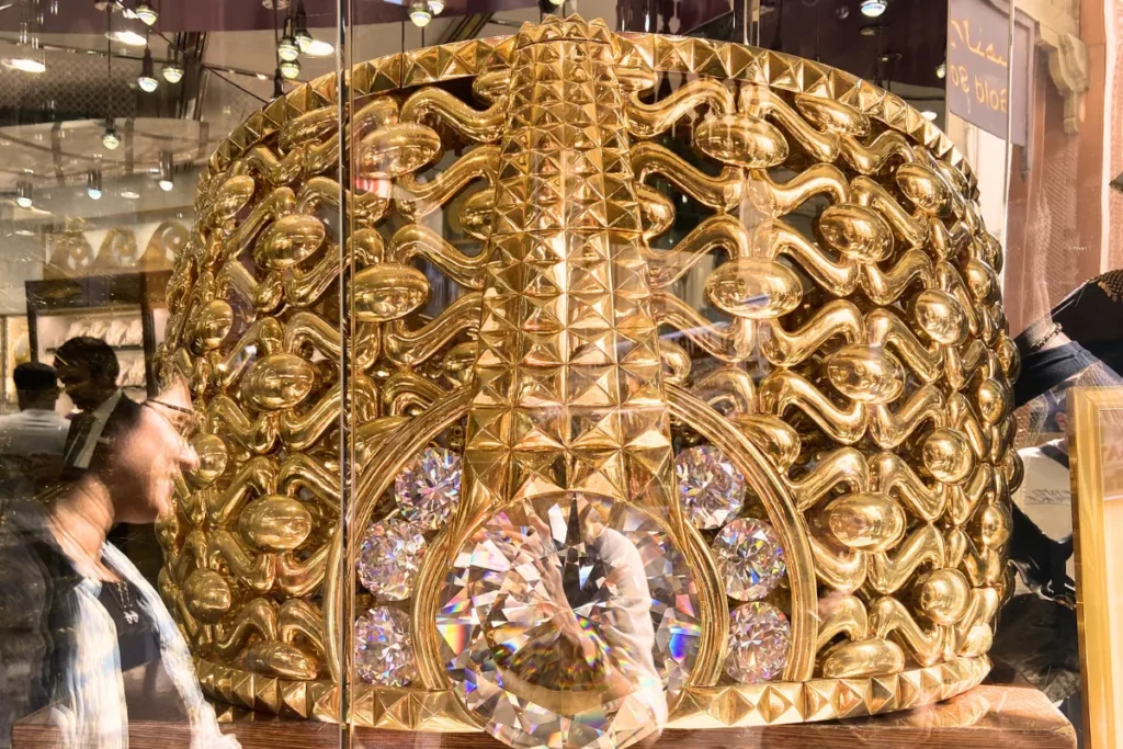 A close-up view of the Najmat Taiba (Star of Taiba), displayed behind glass as the world's largest gold ring, intricately detailed with filigree and stones.