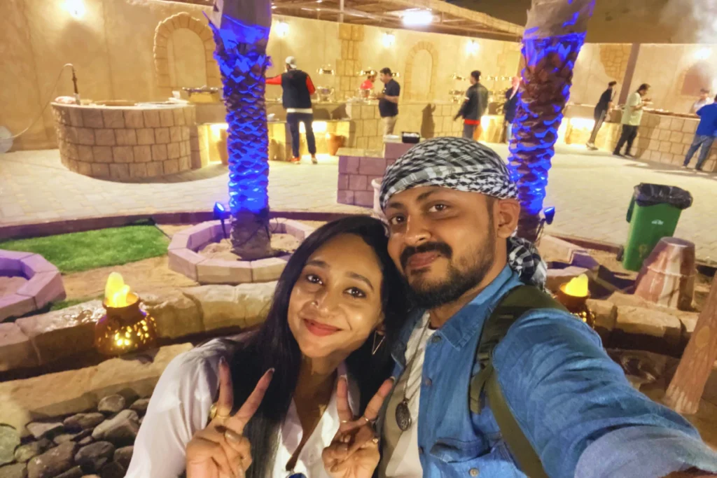 A joyful selfie of Akash and Sumana sitting inside a decorated desert camp tent, with Sumana holding a small falcon on her arm.