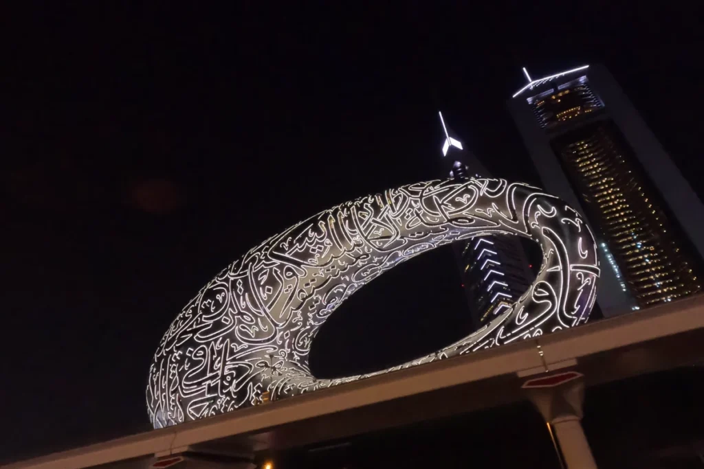 A passenger's point-of-view from inside a car looking out at the metallic, oval-shaped facade of the Museum of the Future in Dubai.