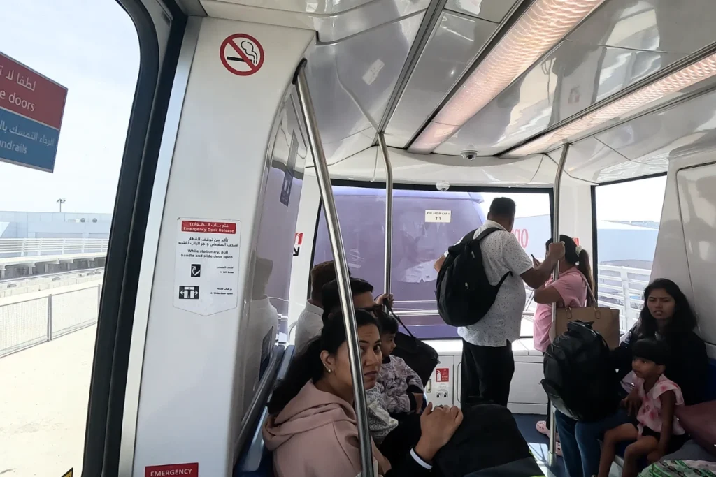  A shot of passengers looking out the large windows of a clean, modern subway car as it passes through an elevated city section.