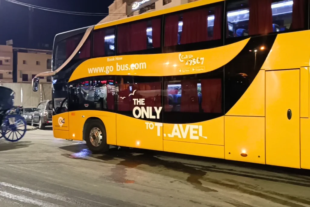 A large, modern orange long-distance commercial travel bus parked outdoors.