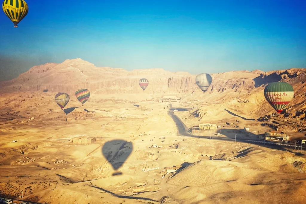A bird's-eye view from a balloon looking down over rocky desert valleys and temple sites.