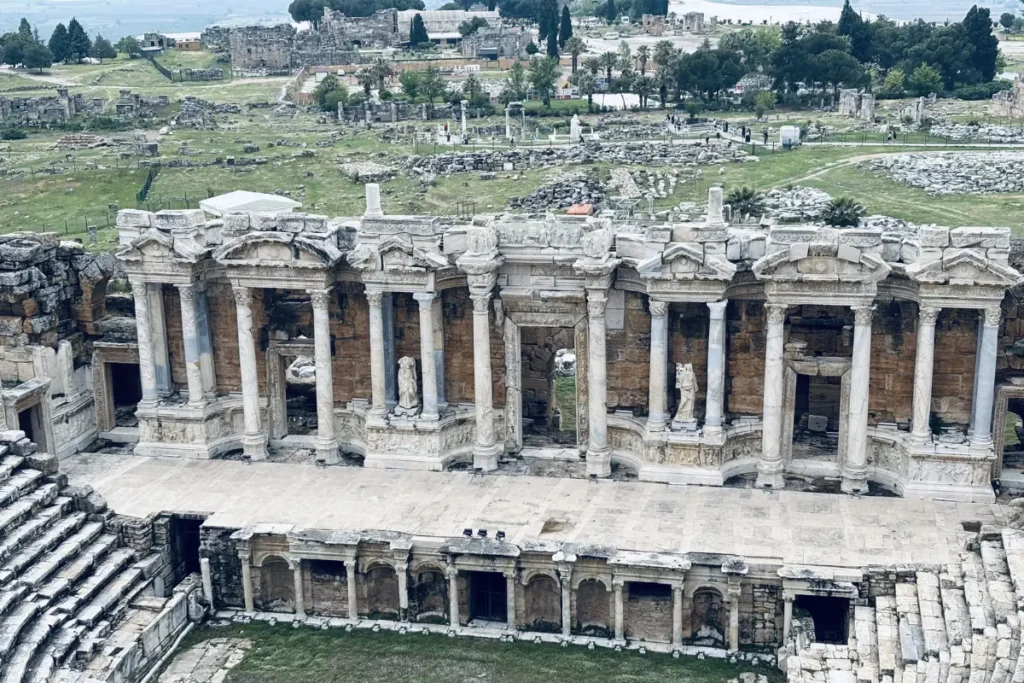 The sprawling, ancient stone ruins of the Roman theater and surrounding structures at Hierapolis.