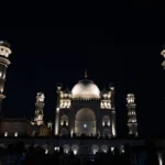 A symmetrical night view of the illuminated Bibi Ka Maqbara in Chhatrapati Sambhajinagar, Maharashtra, showcasing its central marble dome and flanking minarets glowing under dark skies.