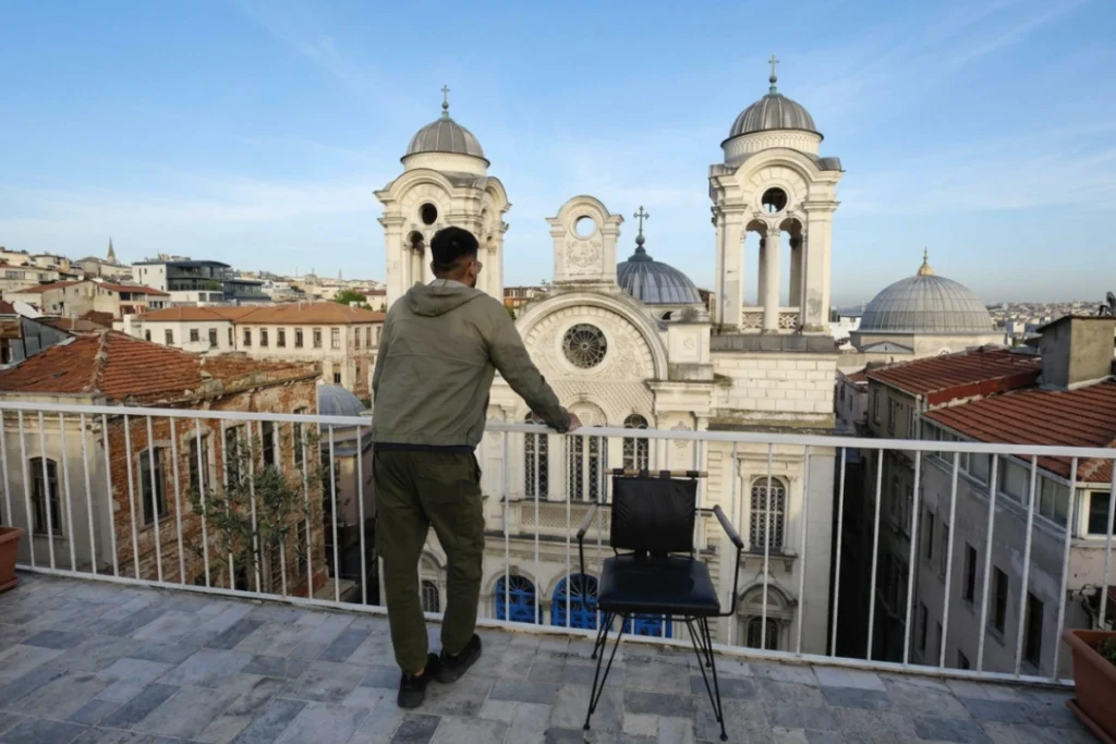 Istanbul- Fatih- Hotel rooftop Akash stands on Global 2022, Fatih hotel rooftop overlooking the surrounding grey domes of historic city architecture under a bright blue sky.