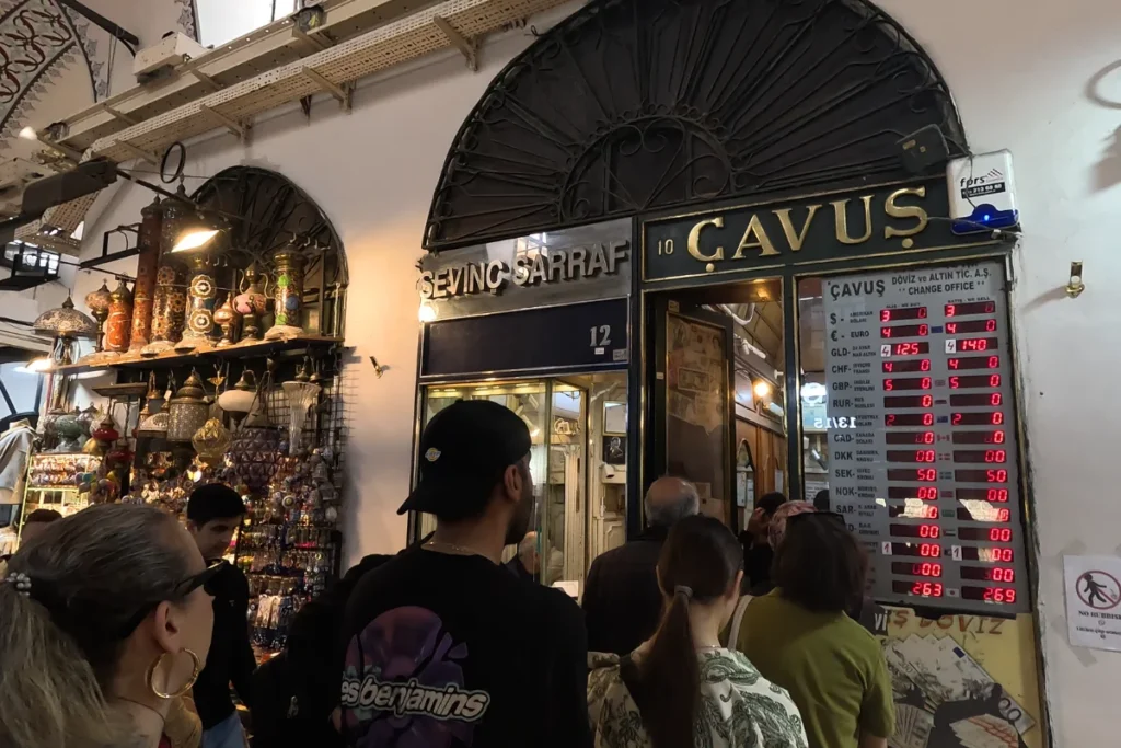 Istanbul- Grand Bazar- Cavus A dark, moody interior shot showing the illuminated glowing sign and counter of a local currency exchange shop.