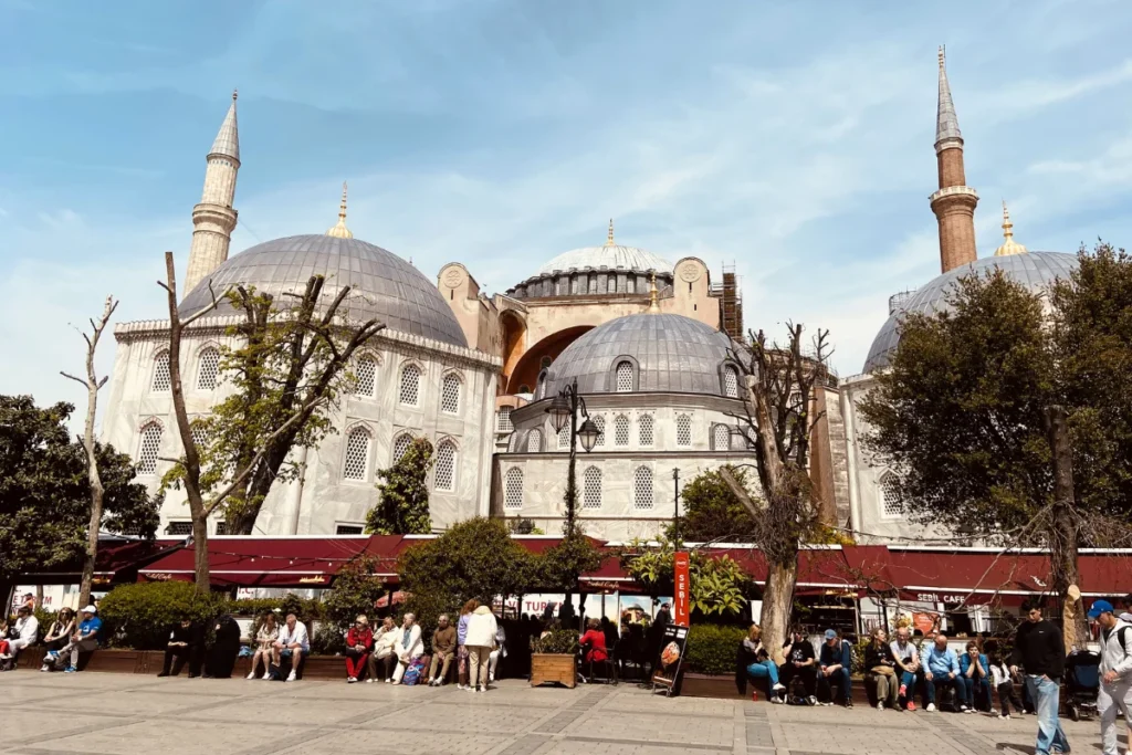 Istanbul- Sulemaniye Mosque- Outside A daytime exterior shot of the sprawling Süleymaniye Mosque complex featuring numerous gray domes, tall minarets, and people milling about the courtyard.