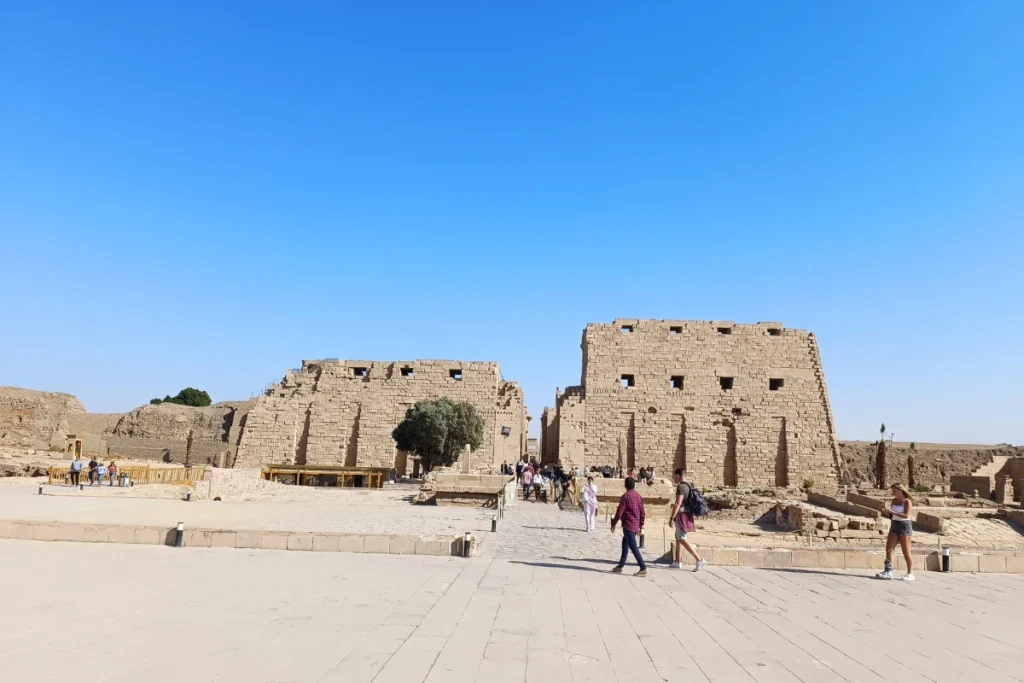A low-angle shot looking up at the towering, intricately carved stone columns of the Hypostyle Hall at Karnak Temple.