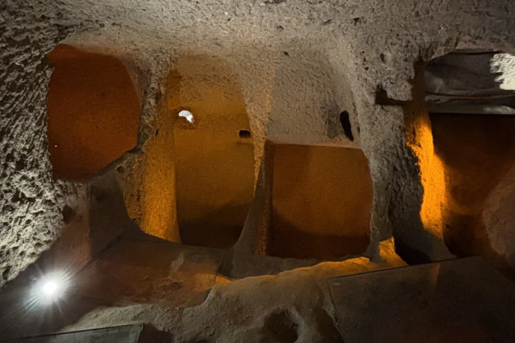 A look into a dim, low-ceilinged volcanic stone corridor illuminated by soft internal museum lighting.