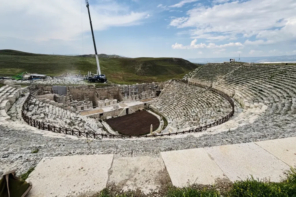 A wide view of a large, remarkably preserved ancient Roman stone amphitheater at Laodicea under a clear sky.