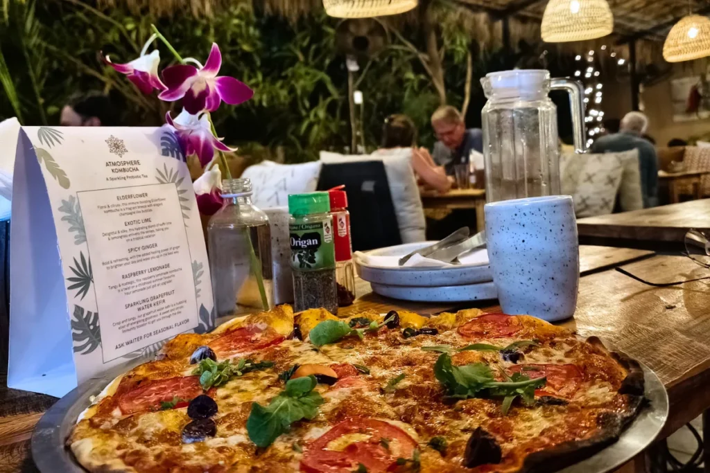 A freshly cooked personal skillet pizza loaded with toppings, served on a restaurant table with a menu visible in the background.