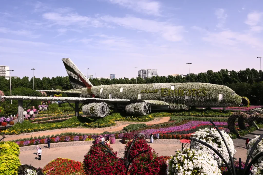 A full-sized Emirates Airbus A380 airplane entirely covered in a vibrant, detailed arrangement of thousands of colorful flowers.
