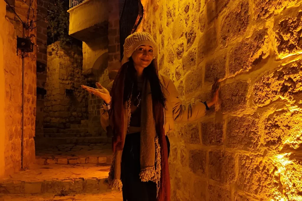 Sumana posing on a narrow stone alleyway in old mardin illuminated by warm streetlights at night.