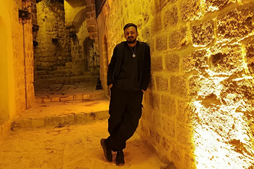 Akash posing on a narrow stone alleyway in old mardin illuminated by warm streetlights at night.
