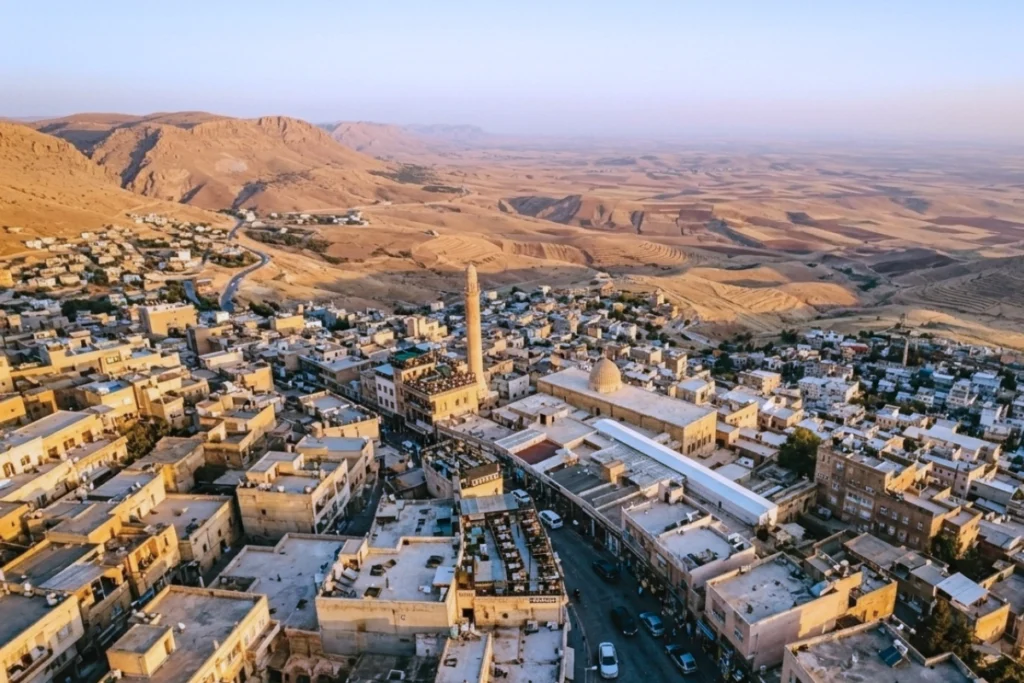Mardin city (1) A sweeping look from a high vantage point across a densely built historic stone town cascading down a hillside.