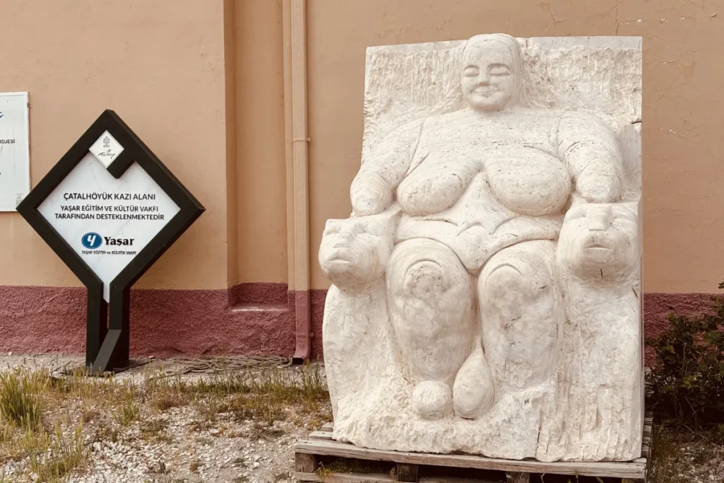 A smooth, ancient stone relief artifact depicting the Seated Woman of Çatalhöyük or Mother Goddess figure flanked by leopards.