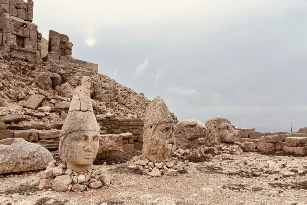 Scattered, colossal stone heads resting on the gravelly ground of the West Terrace of Mount Nemrut.