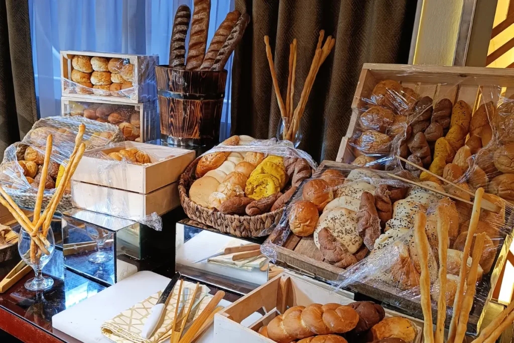 A buffet basket filled with an assortment of flatbreads, rolls, and baked goods.