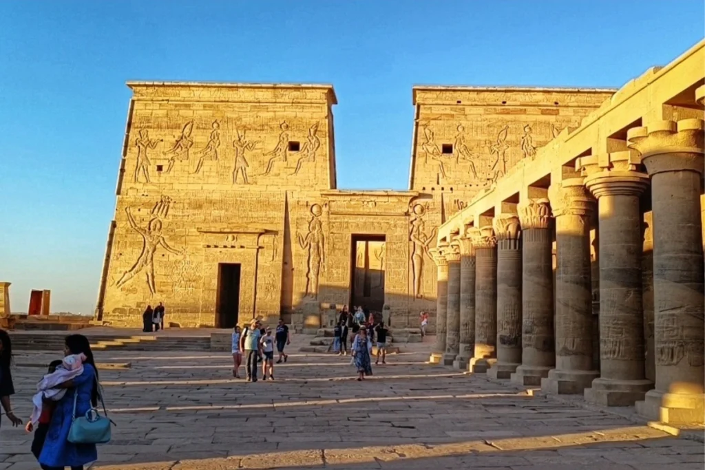 The stone entrance pylons and pillars of the ancient Philae Temple under a bright sky.