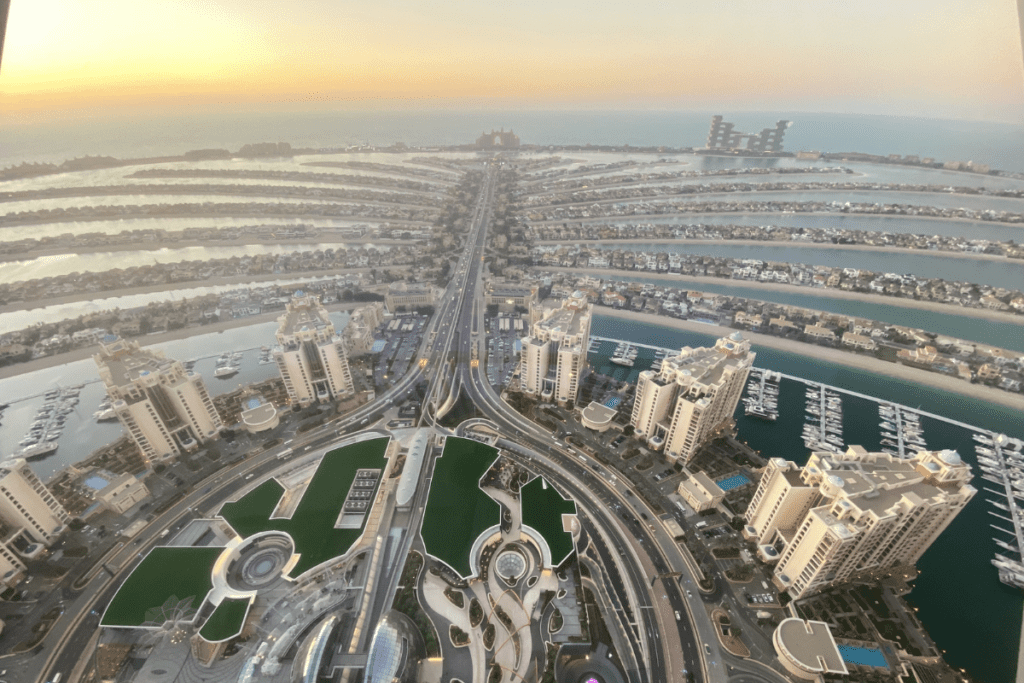 An expansive aerial view looking down onto the palm-tree-shaped artificial archipelago of Palm Jumeirah branching out into the blue sea.