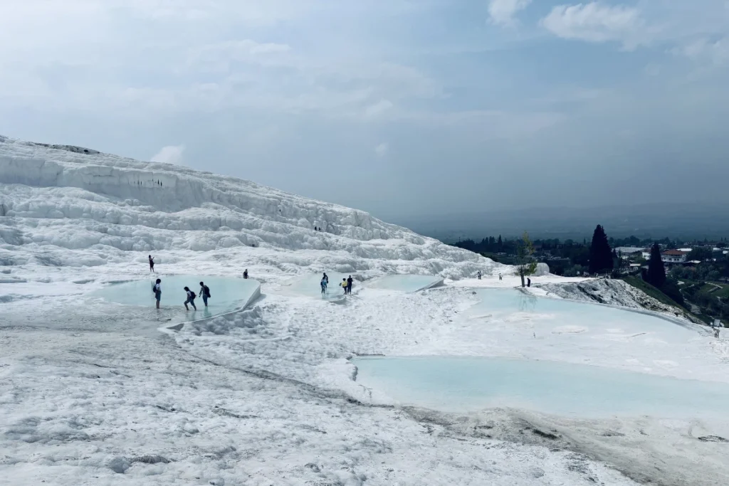 The gleaming white, stepped travertine terraces filled with bright blue thermal water pools at Pamukkale.