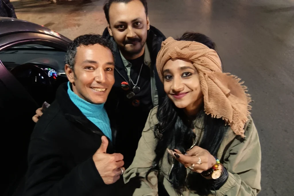 A close-up selfie of Akash & Sumana smiling brightly alongside their guide, Ramy, during their journey.