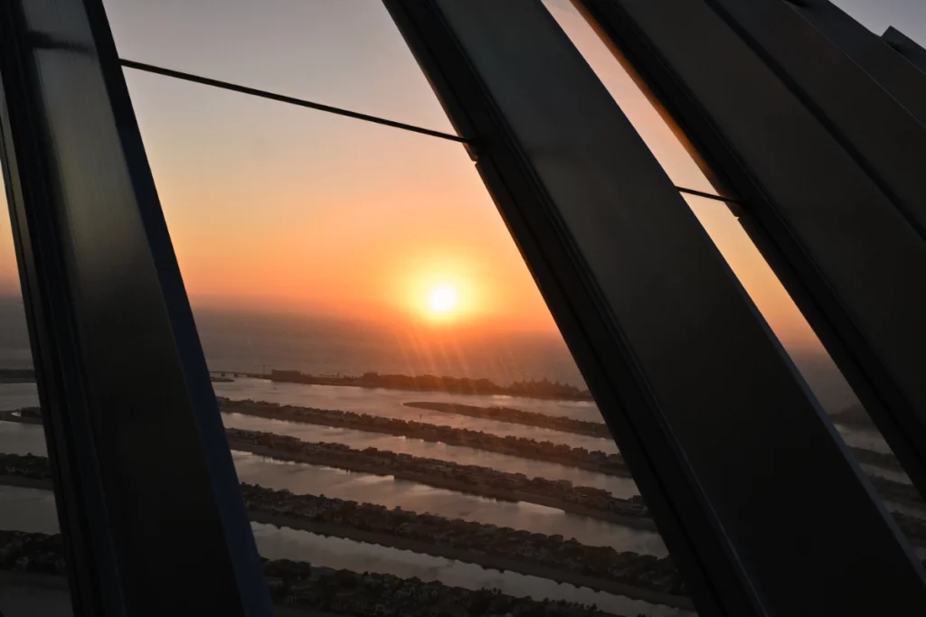 A high-angle view capturing the Palm Jumeirah landscape and surrounding coastal towers during a golden sunset.
