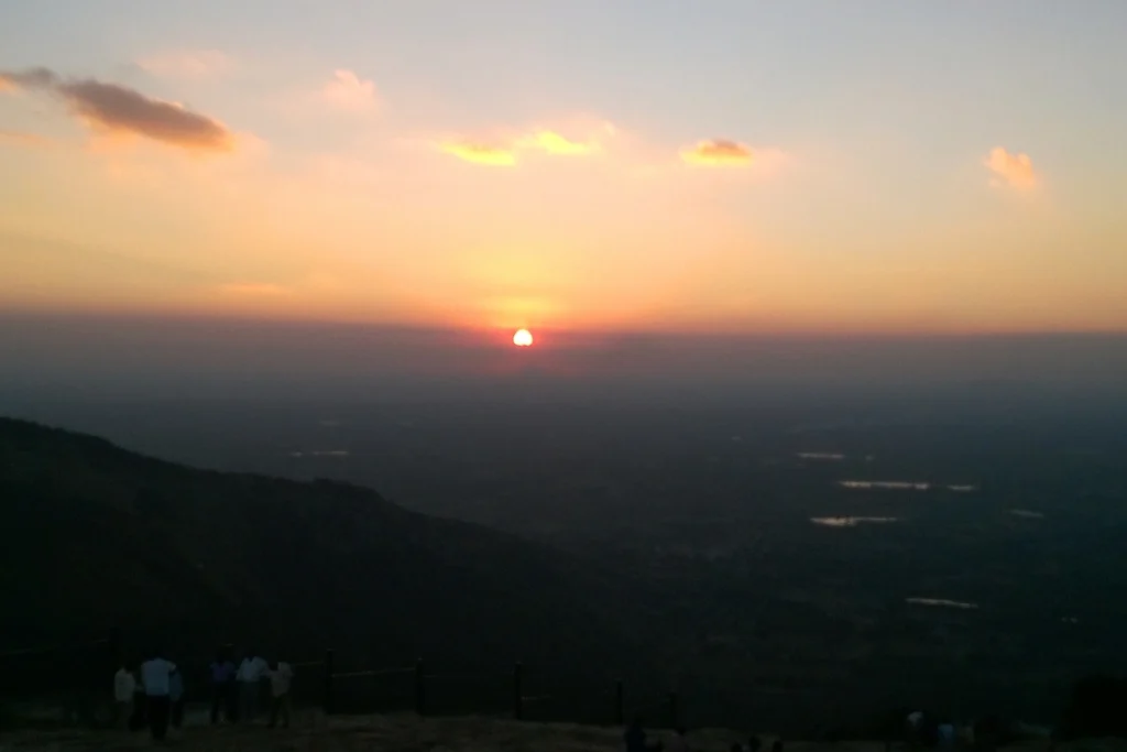 South India- Nandi Hills Sunset A beautiful sunset view over a distant lake and landscape, with the orange sun dipping low on the horizon.