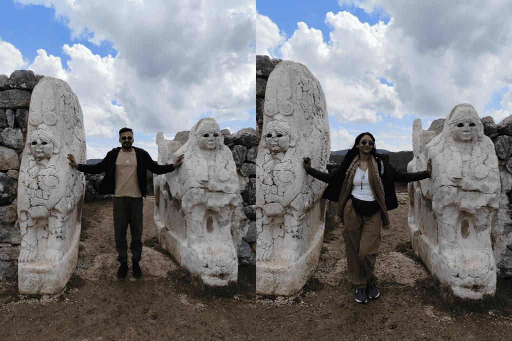 A side-by-side composite photo showing a man on the left and a woman on the right, each standing with their arms outstretched between two large, weathered ancient stone sphinx statues under a blue sky with white clouds.