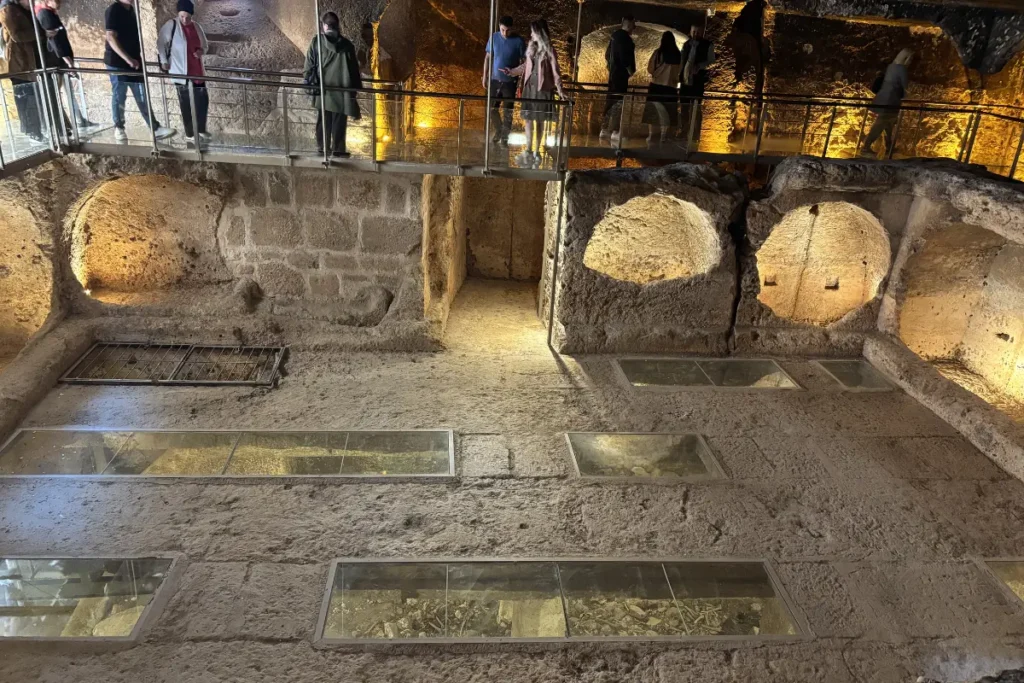 A close-up view of the circular stone openings and chambers inside the illuminated multi-storey gallery grave.