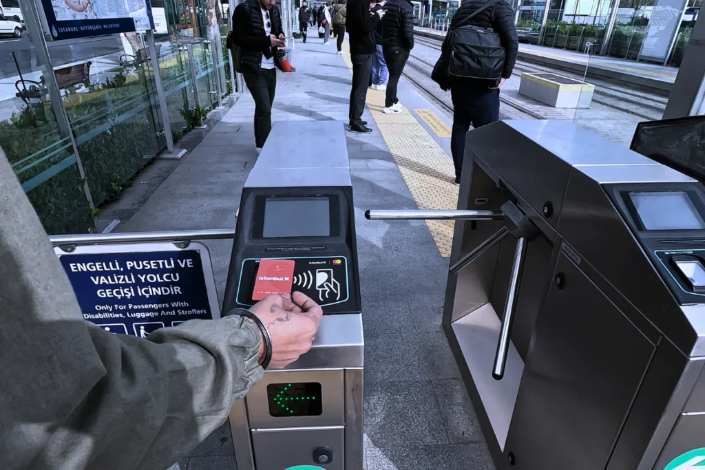 Akash tapping a transit card on a turnstile electronic reader at an Istanbul tram station.