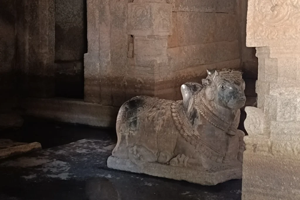 A dimly lit view of a stone Nandi bull statue standing inside a partially flooded chamber of the Underground Shiva Temple.
