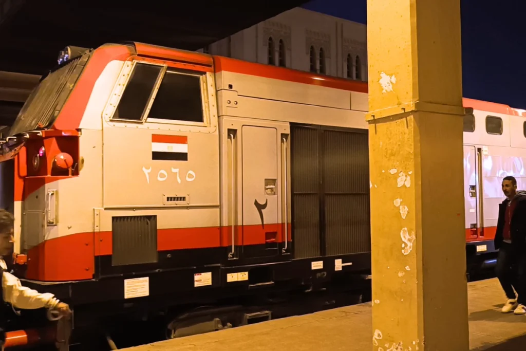An orange and cream-colored train engine parked at a terminal platform in Cairo.