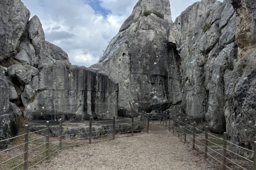Ancient rock-cut reliefs depicting a procession of Hittite deities carved into a narrow, vertical limestone rock cleft at Yazılıkaya.