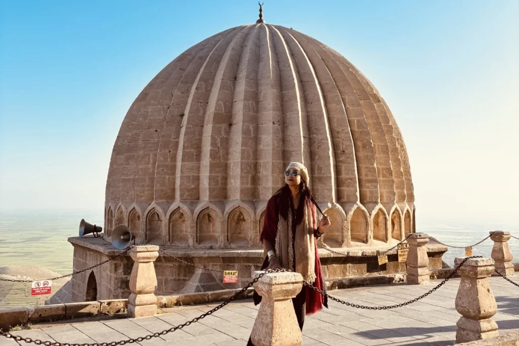 A close-up of a stone dome of the Zinciriye Madrasa in Mardin with Sumana standing under it.