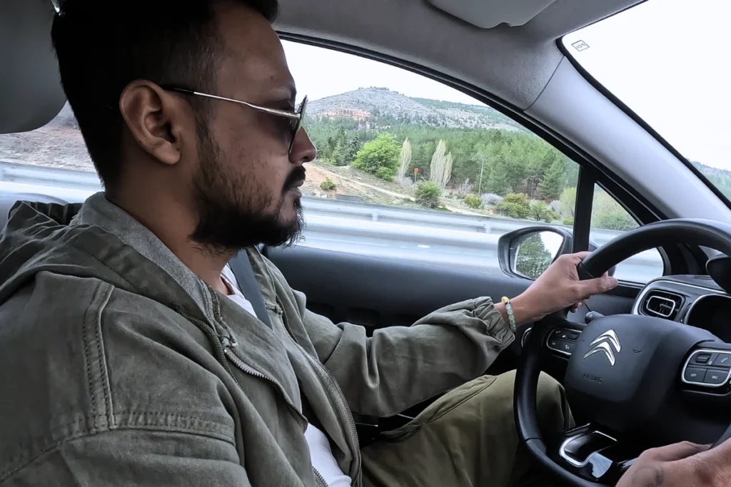 Profile view of a man driving a rental vehicle, focusing on the road ahead.