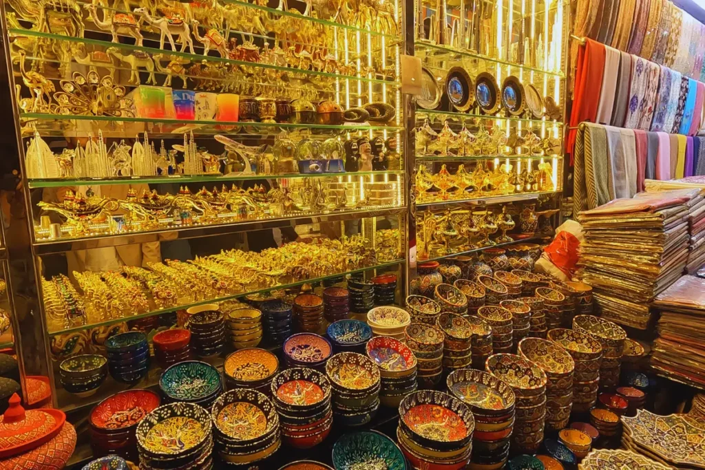 Dubai- Shop Shelves inside a store stacked high with a variety of colorful patterned ceramic bowls, metallic camel figurines, and traditional Middle Eastern souvenirs.