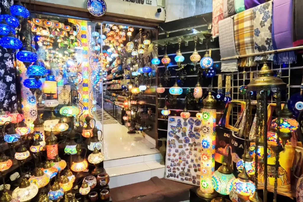 Dubai- creek side shop An view of a vibrant market stall completely filled with glowing, multi-colored glass lamps and mosaic lanterns hanging from the ceiling and stacked on shelves.