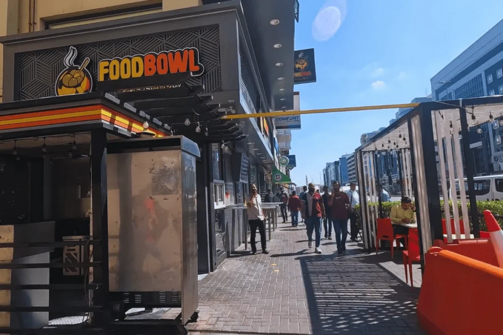 Dubai- food bowl A street view of a pedestrian lane in a commercial district featuring a restaurant with a "Food Bowl" sign.