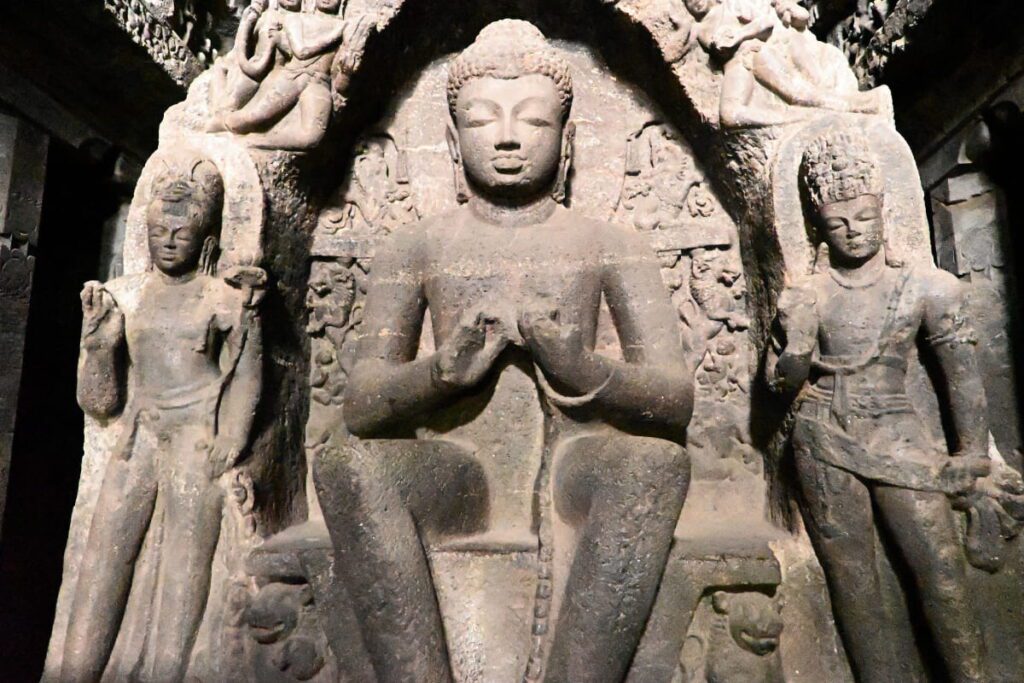 Ellora cave 1 Intricately carved stone statues and relief sculptures of Buddha flanked by attendants along a wall inside the Buddhist caves at Ellora.