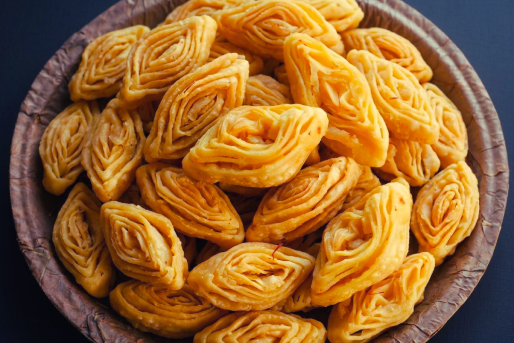 KHAJA A plate filled with crispy, golden-brown layers of Khaja, a traditional sweet delicacy.