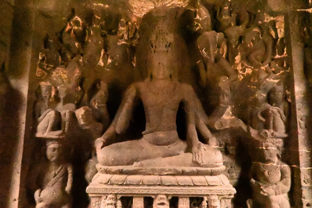 Kailash Temple 2 An interior view of an ancient carved stone shrine room with detailed columns and figures inside the Ellora Caves complex.